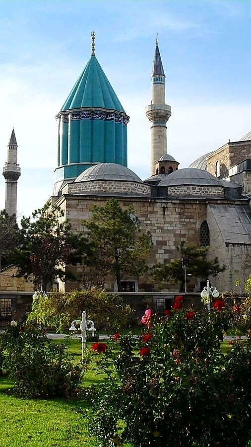 This may contain: an old building with two blue domes on it's roof and flowers in the foreground