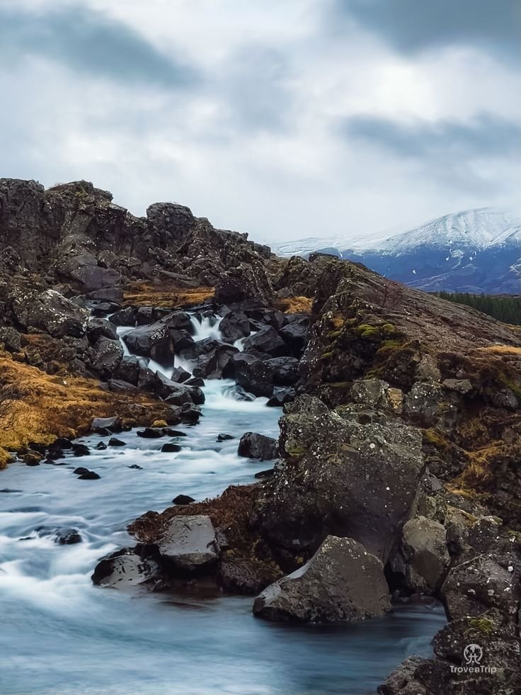 This may contain: the water is rushing down the rocks in the mountains