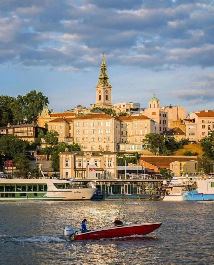This may contain: a man in a red boat on the water near some buildings and a clock tower