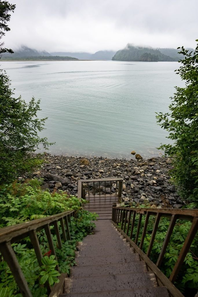 This may contain: stairs lead down to the water from an area with rocks and plants on either side