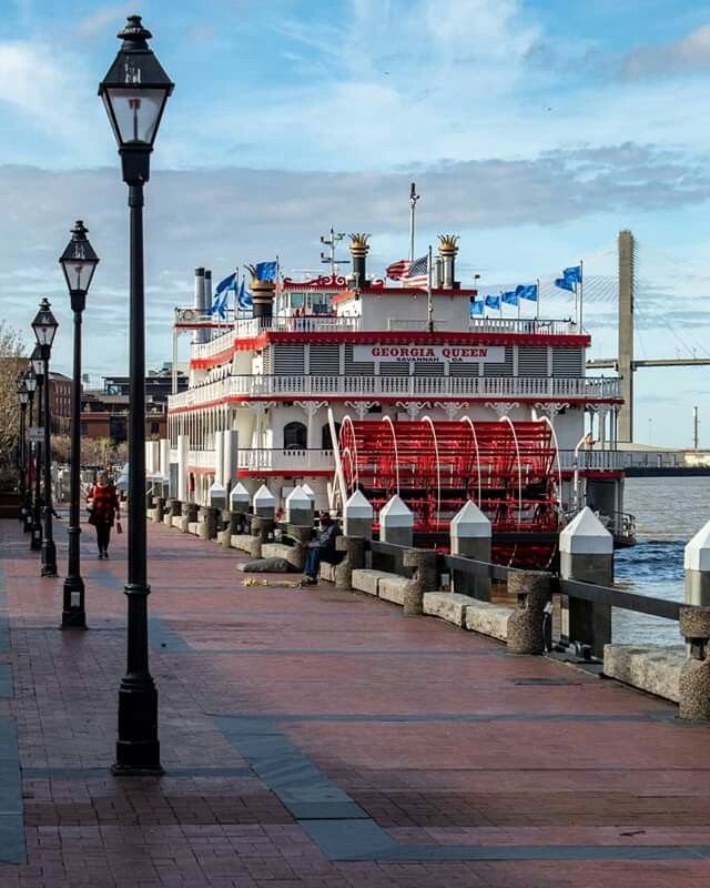 This may contain: a large red and white boat docked next to a light pole on the side of a river