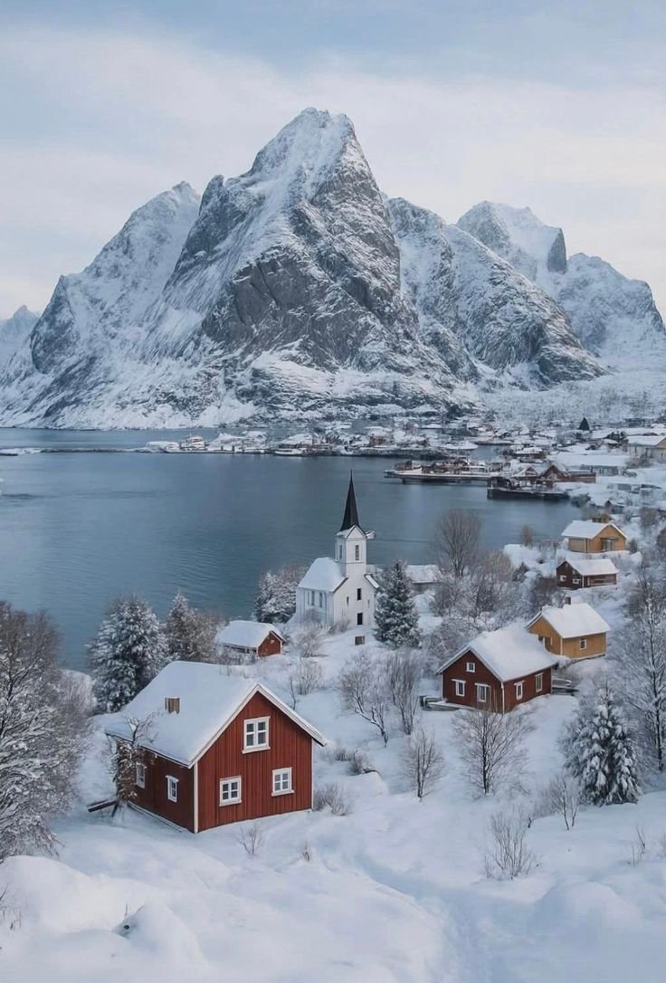 This may contain: a small village in the middle of snow covered mountains and water with houses on it