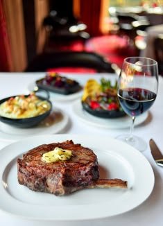 This may contain: a plate with steak, salad and wine on it
