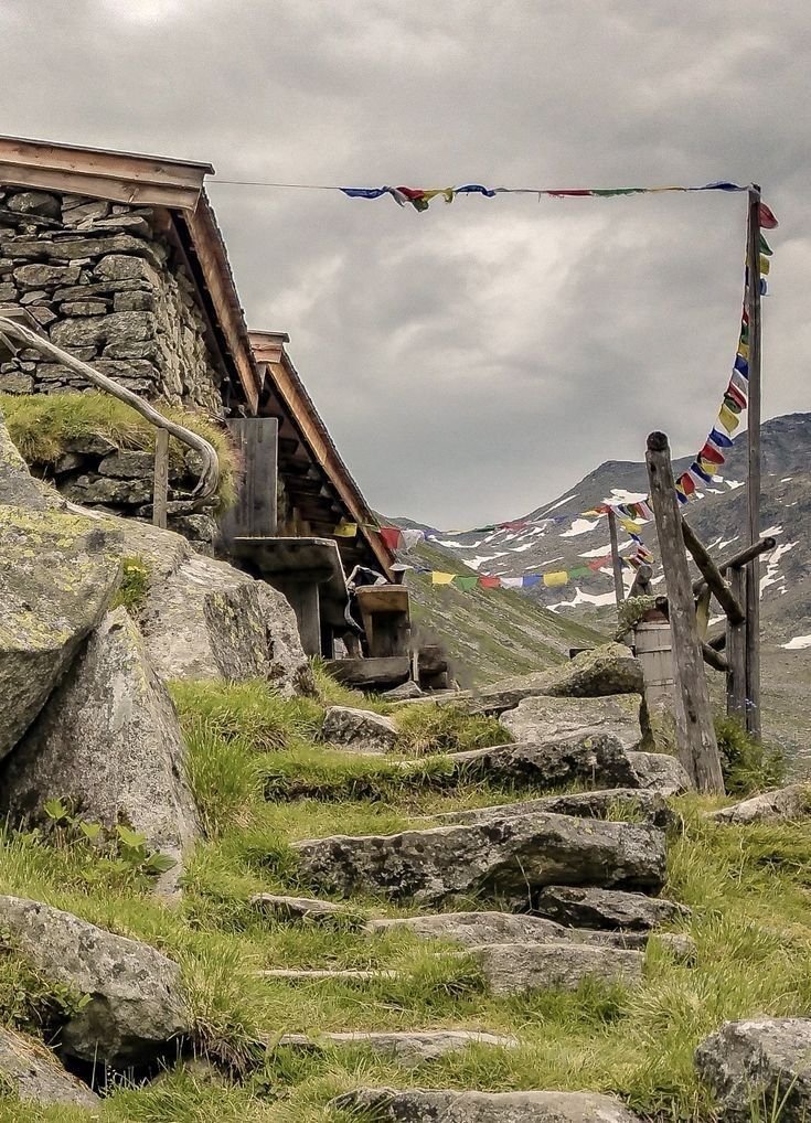 This may contain: there are many flags flying in the sky above some rocks and grass on this mountain side