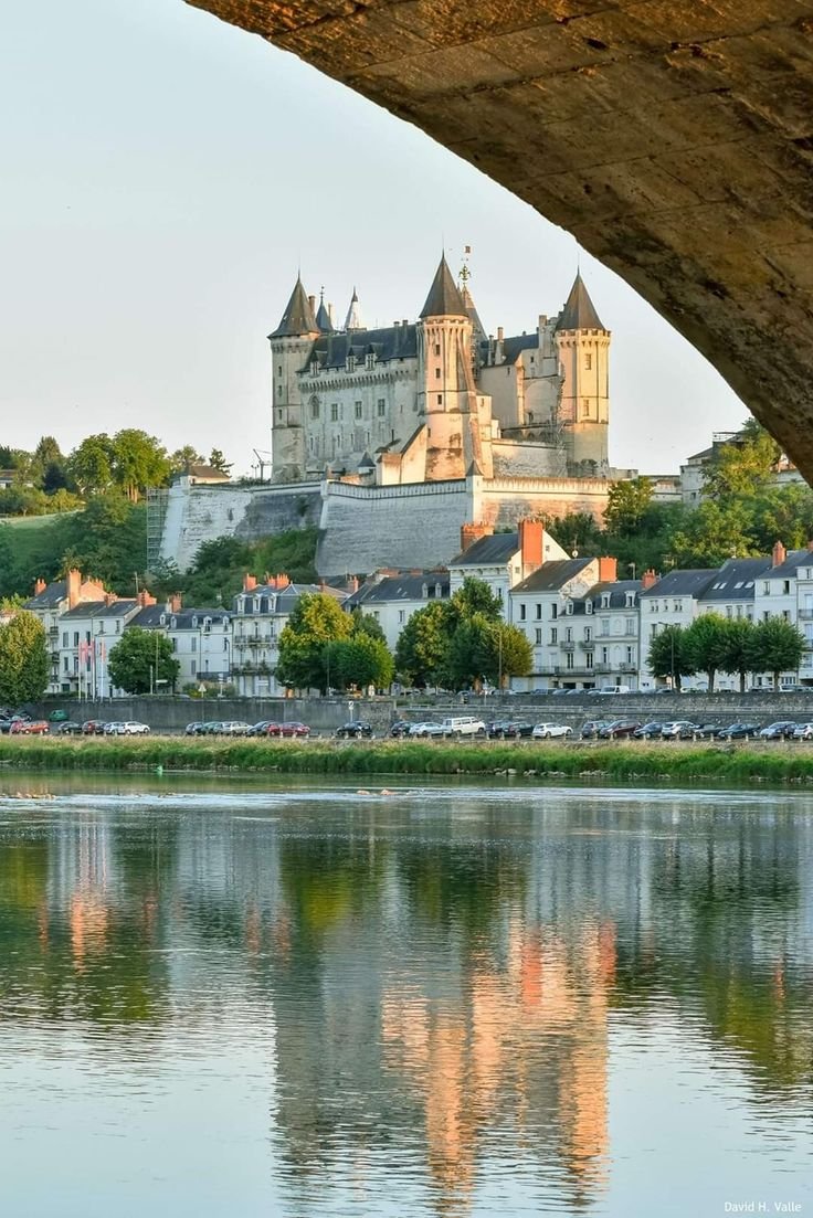This may contain: an old castle sits on top of a hill next to a body of water