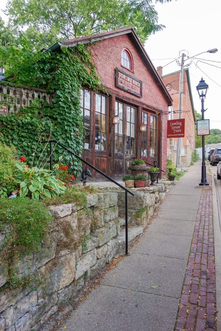This may contain: an old brick building with vines growing on it's side and the sidewalk next to it