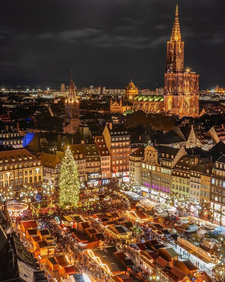 This may contain: an aerial view of a city at night with christmas trees and lights on the buildings