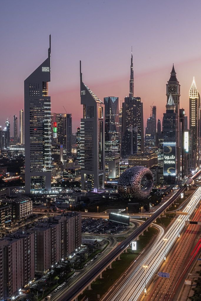 This may contain: the city skyline is lit up at night with many tall buildings and skyscrapers in the background