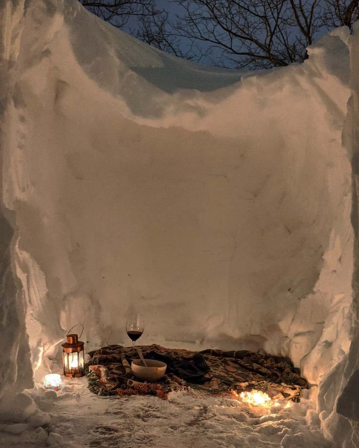 This may contain: an igloose with candles in the middle and snow on the ground next to it
