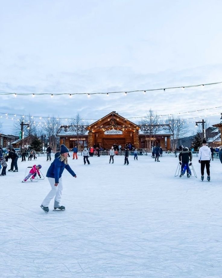 This may contain: a group of people riding snowboards on top of a snow covered slope in front of a building