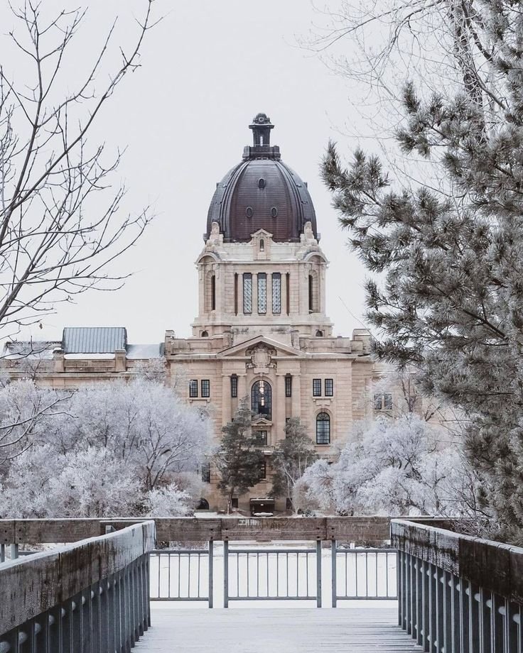 This may contain: a large building with a dome on top in the middle of trees and snow covered ground