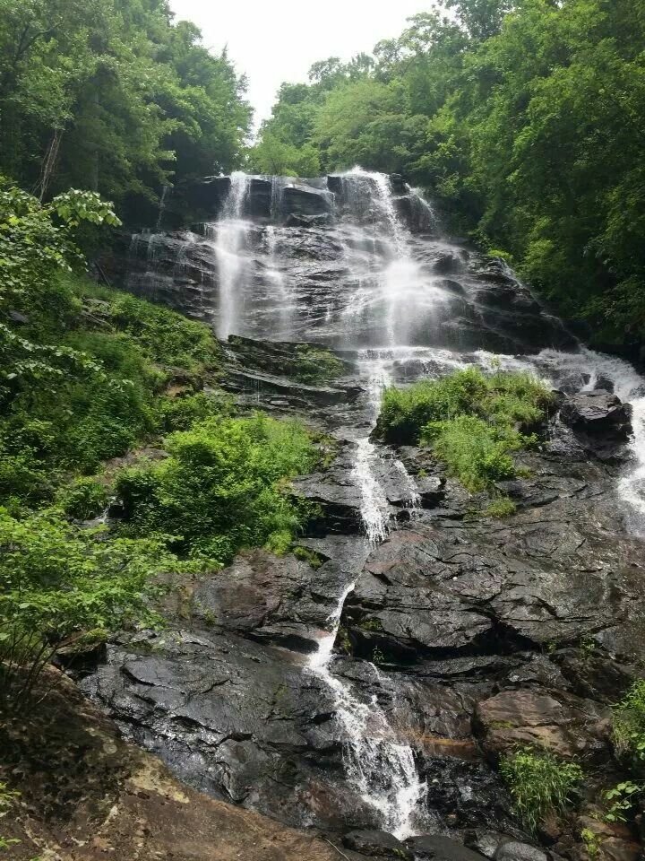 This may contain: a large waterfall surrounded by lush green trees