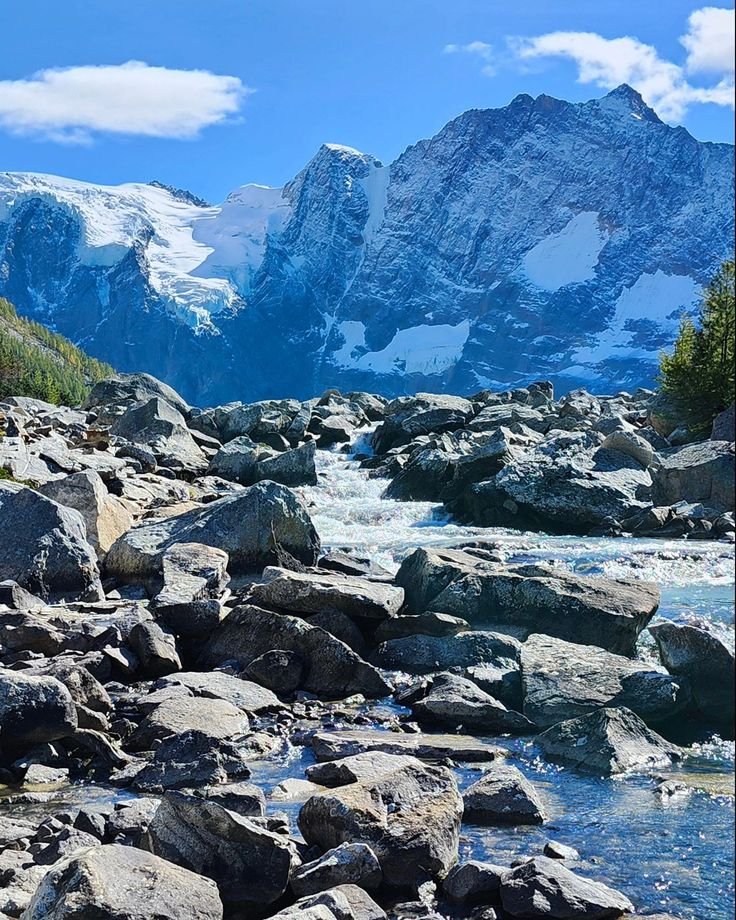 This may contain: a rocky river with mountains in the background