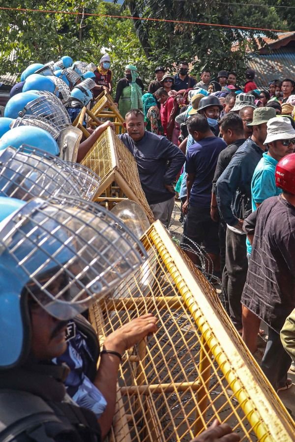 This may contain: a crowd of people standing next to each other in front of cages filled with birds