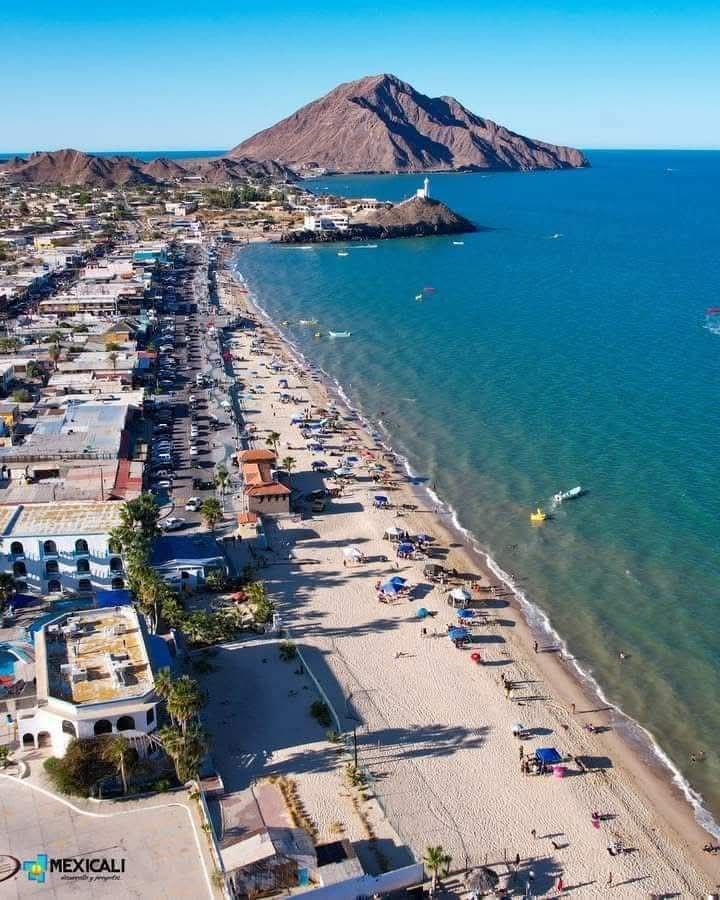 This may contain: an aerial view of the beach and ocean with mountains in the backgrouds