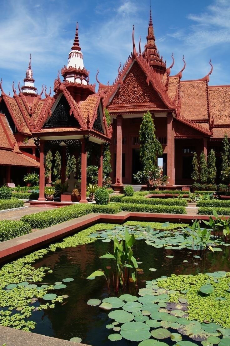 This may contain: an ornate building with water lilies in the foreground and green plants on either side