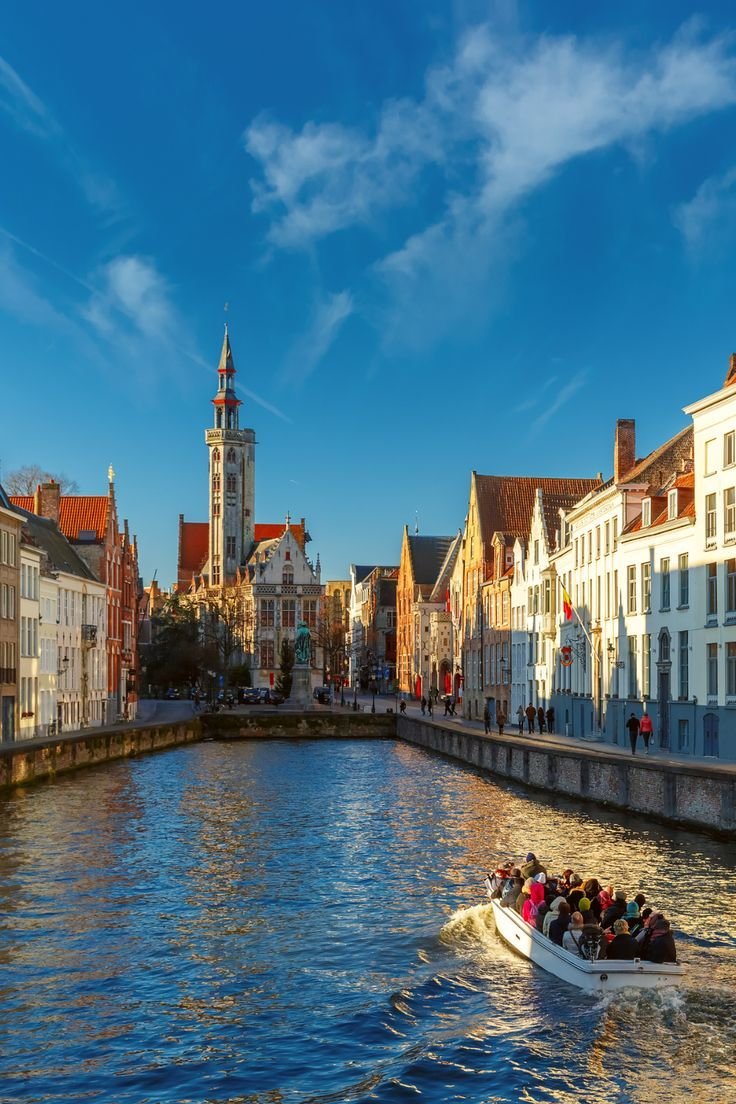 This may contain: a boat filled with people traveling down a river next to tall buildings