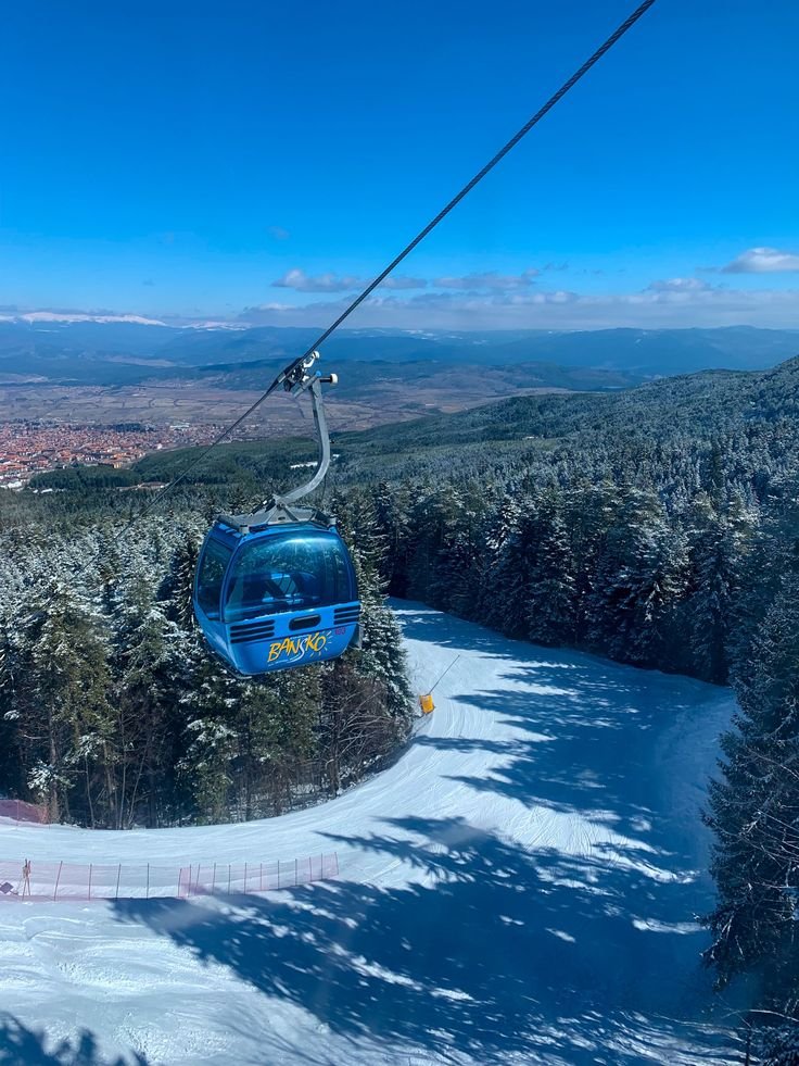 This may contain: a blue cable car going over a snow covered hill