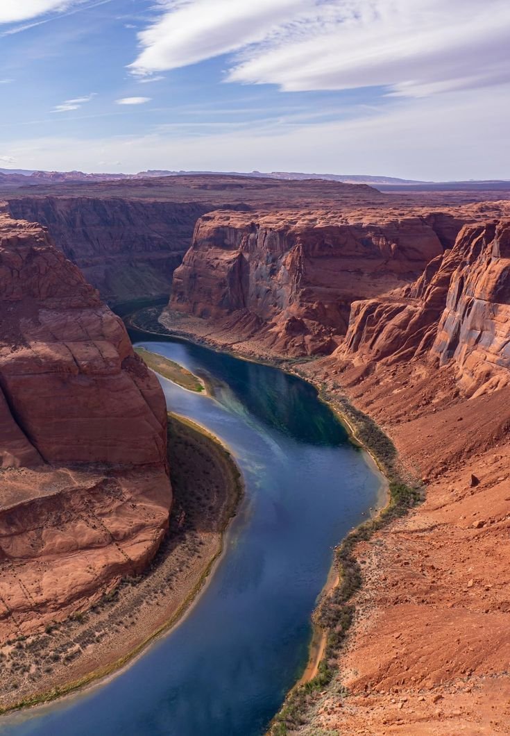 This may contain: an aerial view of the river and canyons in the desert, with blue water