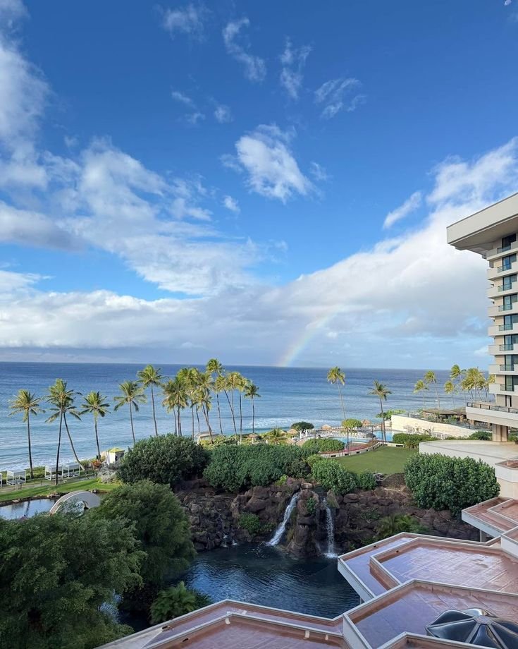 This may contain: a rainbow is seen over the ocean in this view from an apartment building on the beach