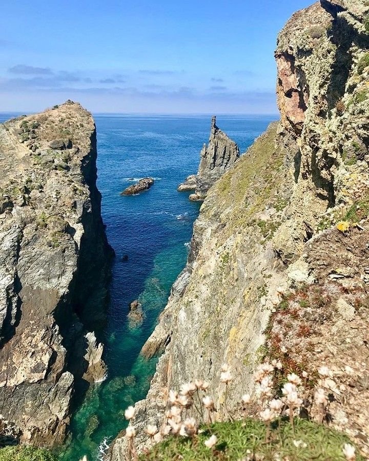 This may contain: an ocean view from the top of a mountain with some rocks and water in it