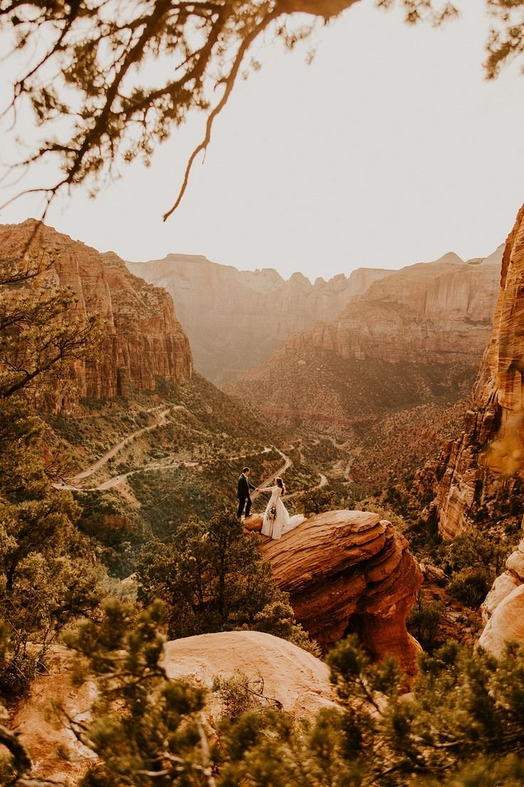 This may contain: a man and woman standing on top of a mountain next to each other in the mountains