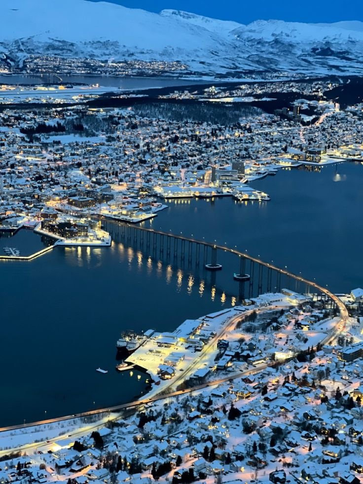 This may contain: an aerial view of a city with snow on the ground and mountains in the background