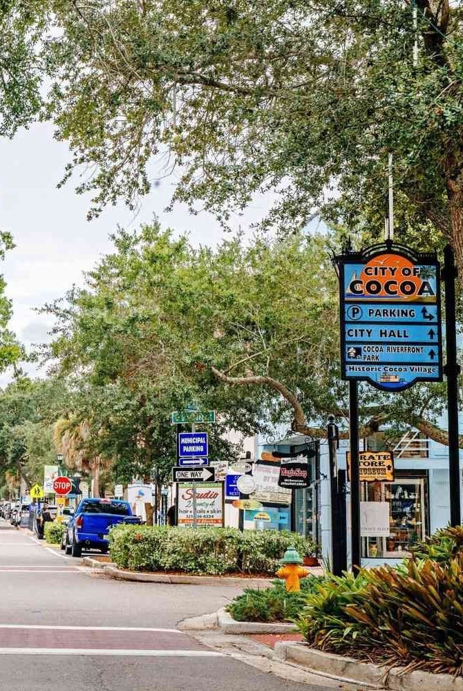 This may contain: a city street with trees and signs on the side of the road in front of it