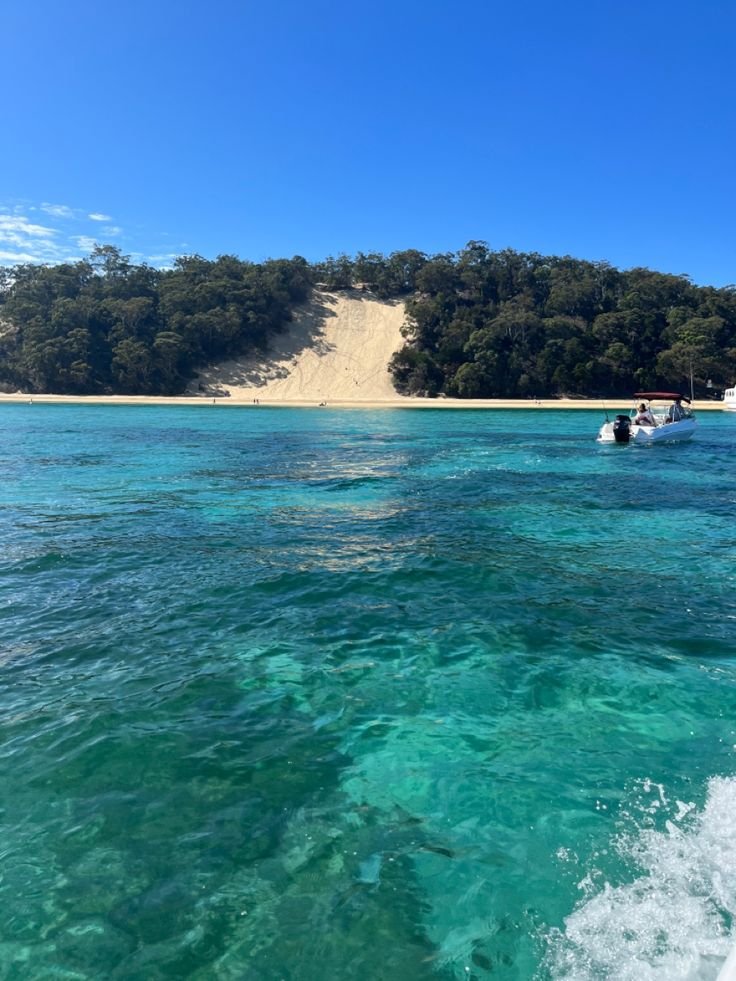 This may contain: the water is crystal blue and clear with people on boats in front of an island