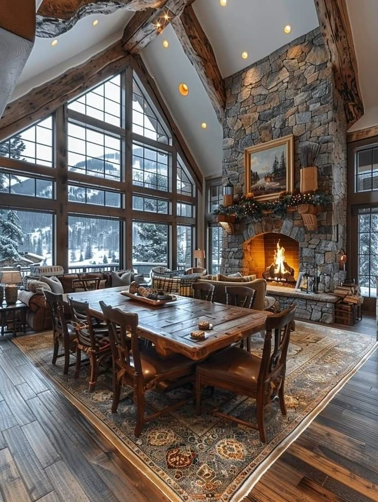 This may contain: a dining room table with chairs and a fire place in the center surrounded by large windows