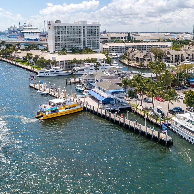 This may contain: boats are docked in the water next to buildings and palm trees on either side of the pier