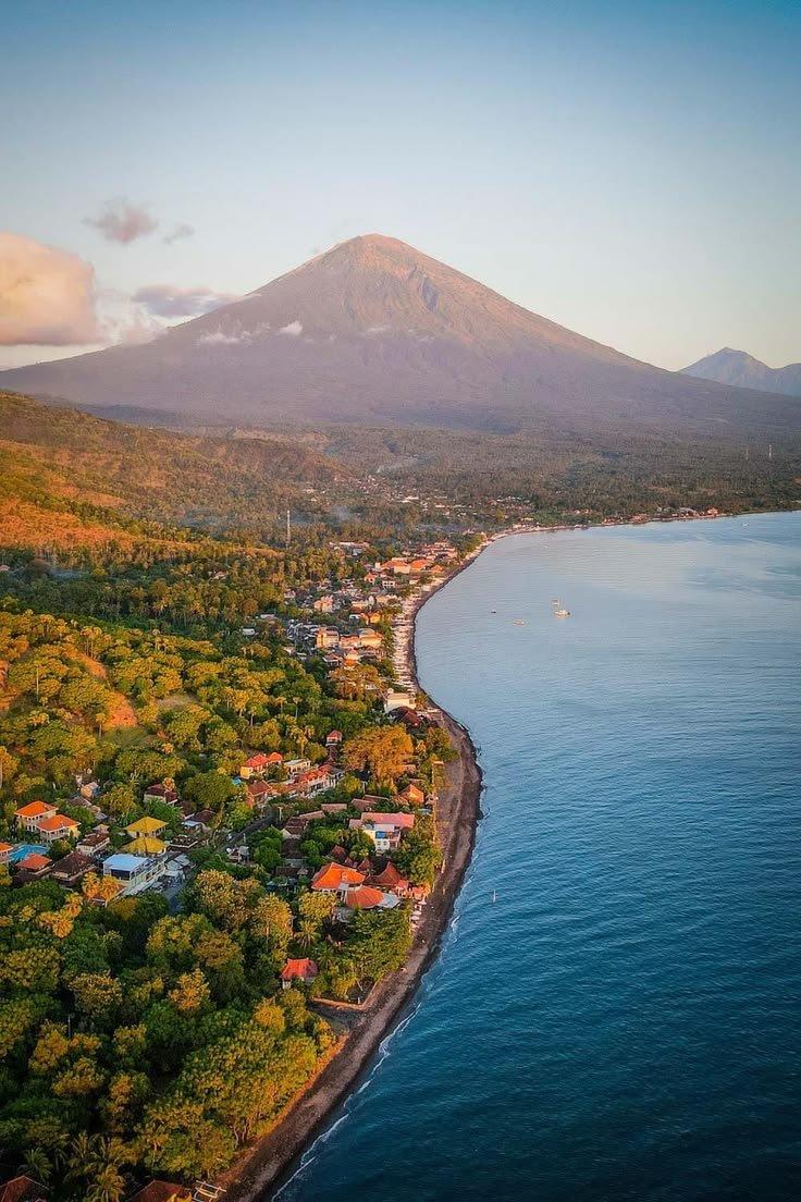 This may contain: an aerial view of a small town by the water with a mountain in the background