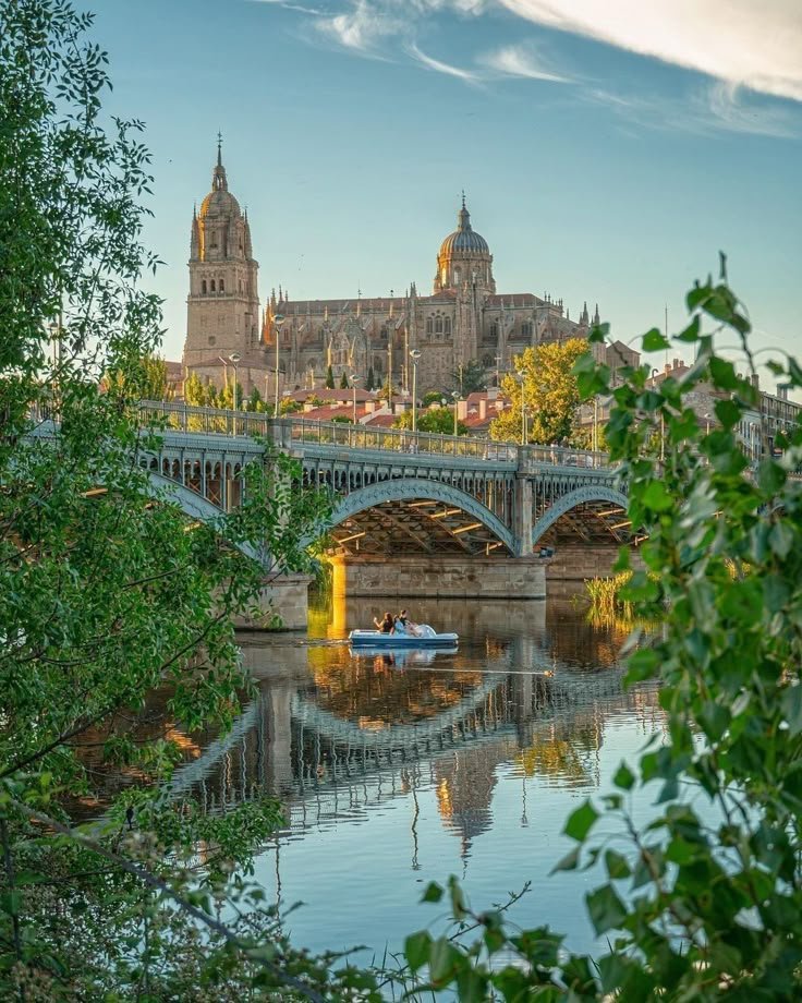 This may contain: there is a boat on the water in front of a bridge and castle like building