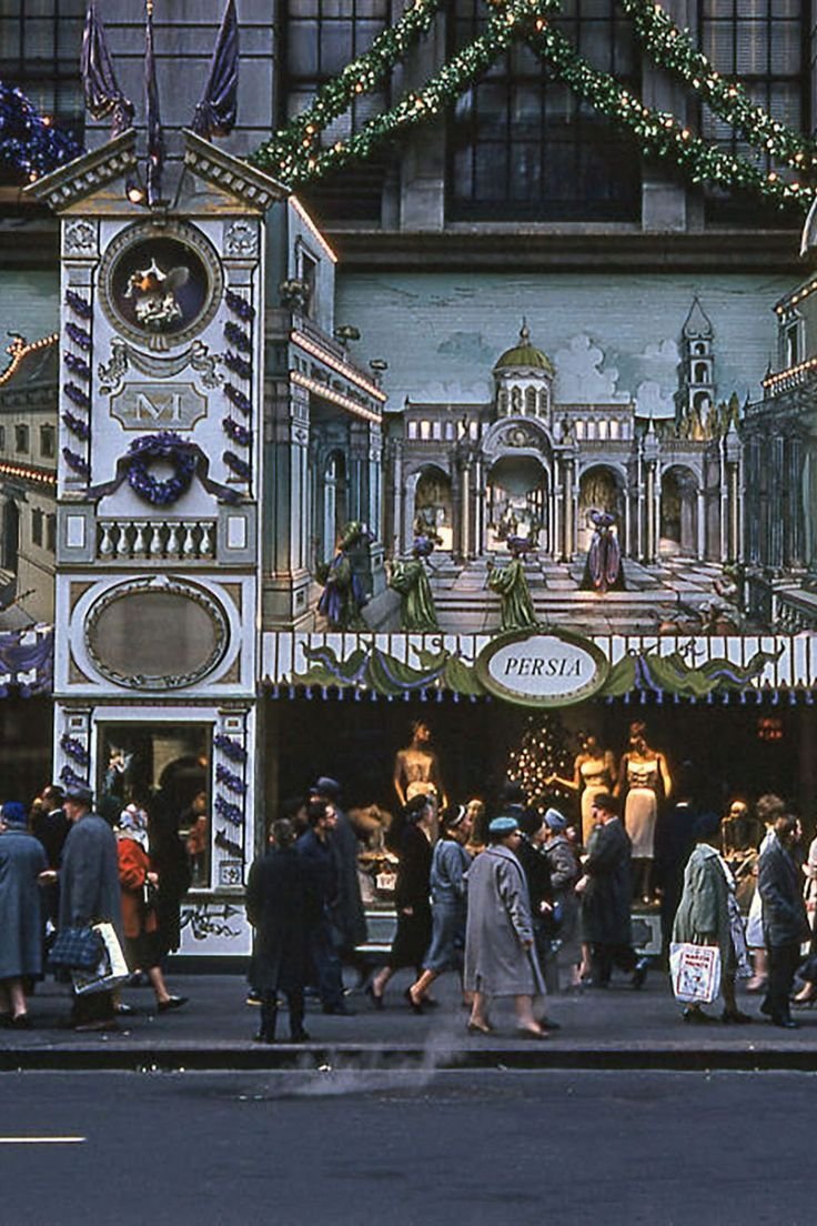 This may contain: many people are walking in front of a building decorated with christmas lights and garlands
