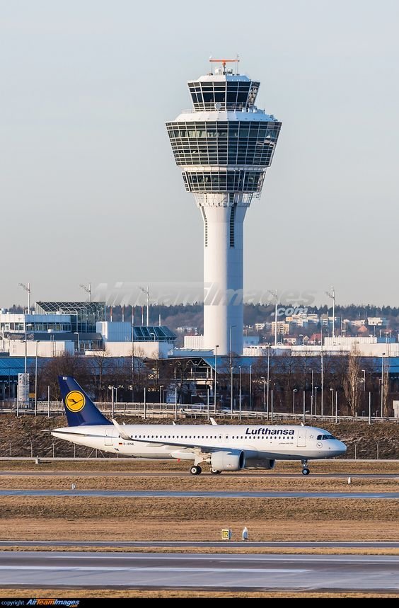 This may contain: an airplane is sitting on the runway in front of a control tower at an airport