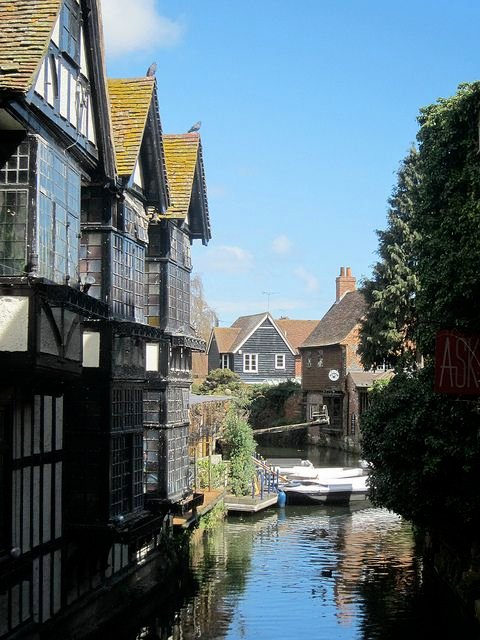 This may contain: there is a boat that is going down the river in this town with houses on both sides