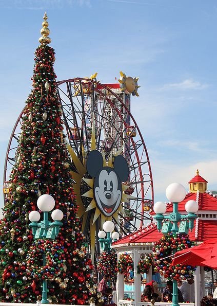 This may contain: the mickey mouse christmas tree is in front of an amusement park