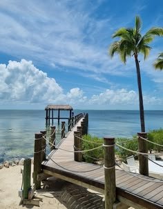 This may contain: a wooden dock on the beach with palm trees