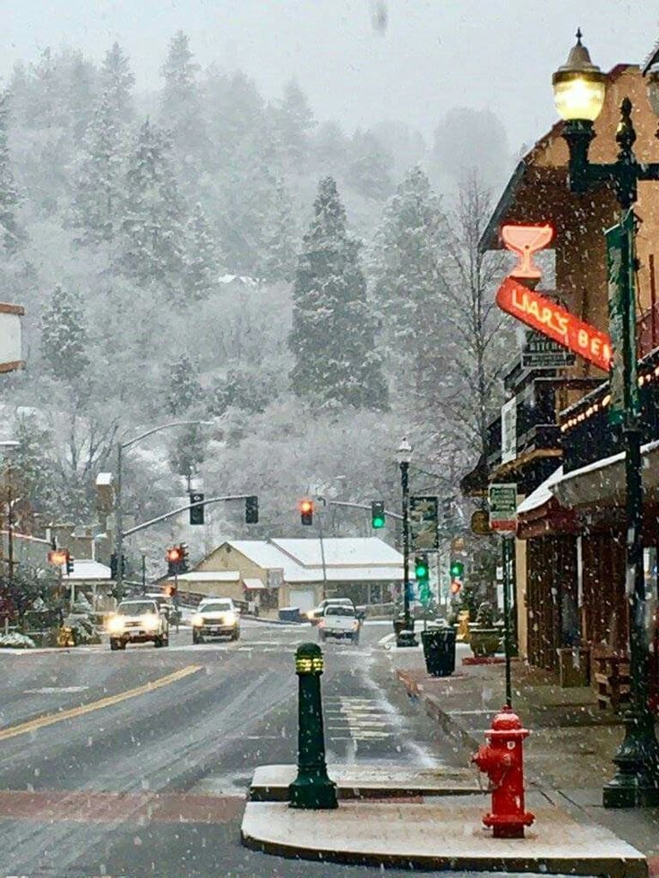This may contain: a snow covered street with cars driving down it