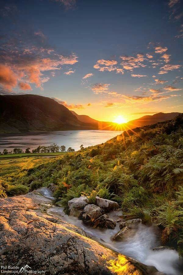 This may contain: the sun is setting over a mountain and river
