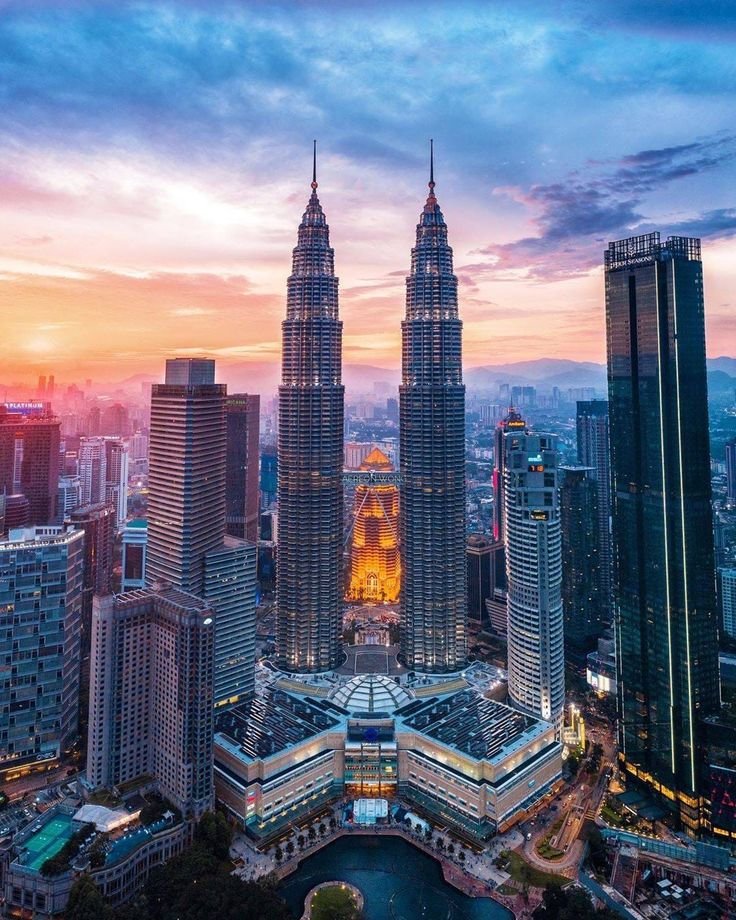 This may contain: an aerial view of some very tall buildings in the middle of a city at sunset