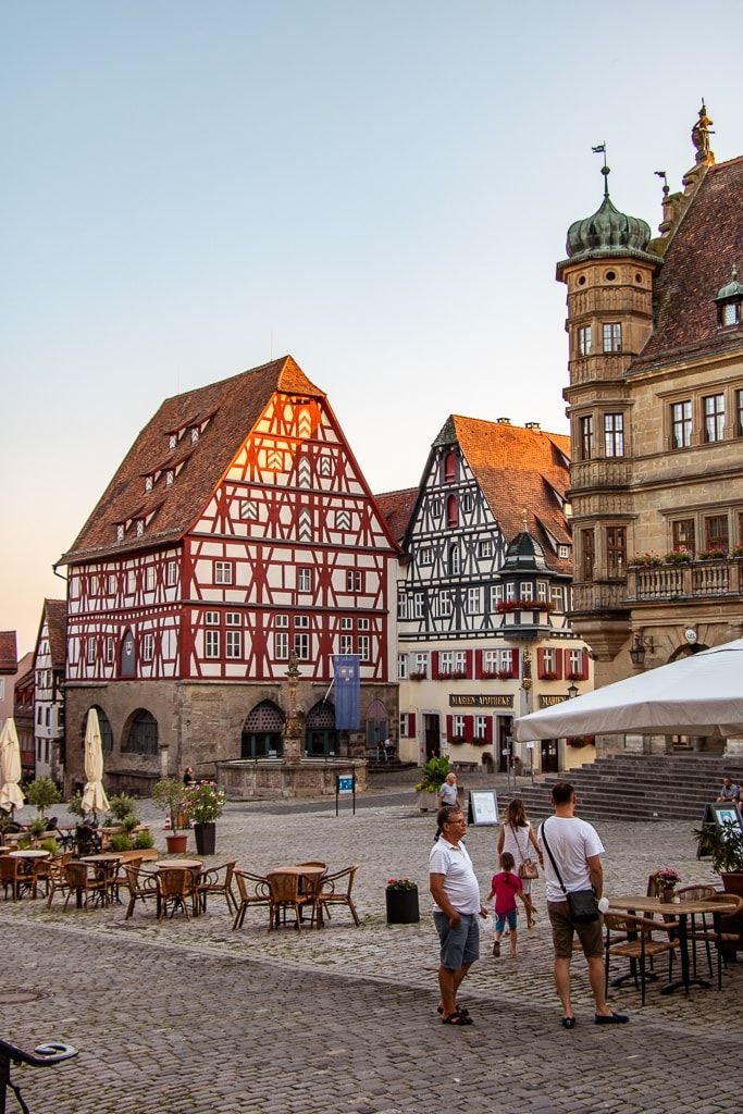 This may contain: people are walking around in front of some old buildings on a cobblestone street