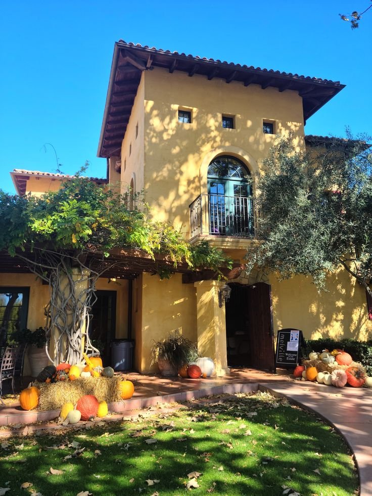 This may contain: a house with pumpkins and gourds in the front yard on a sunny day