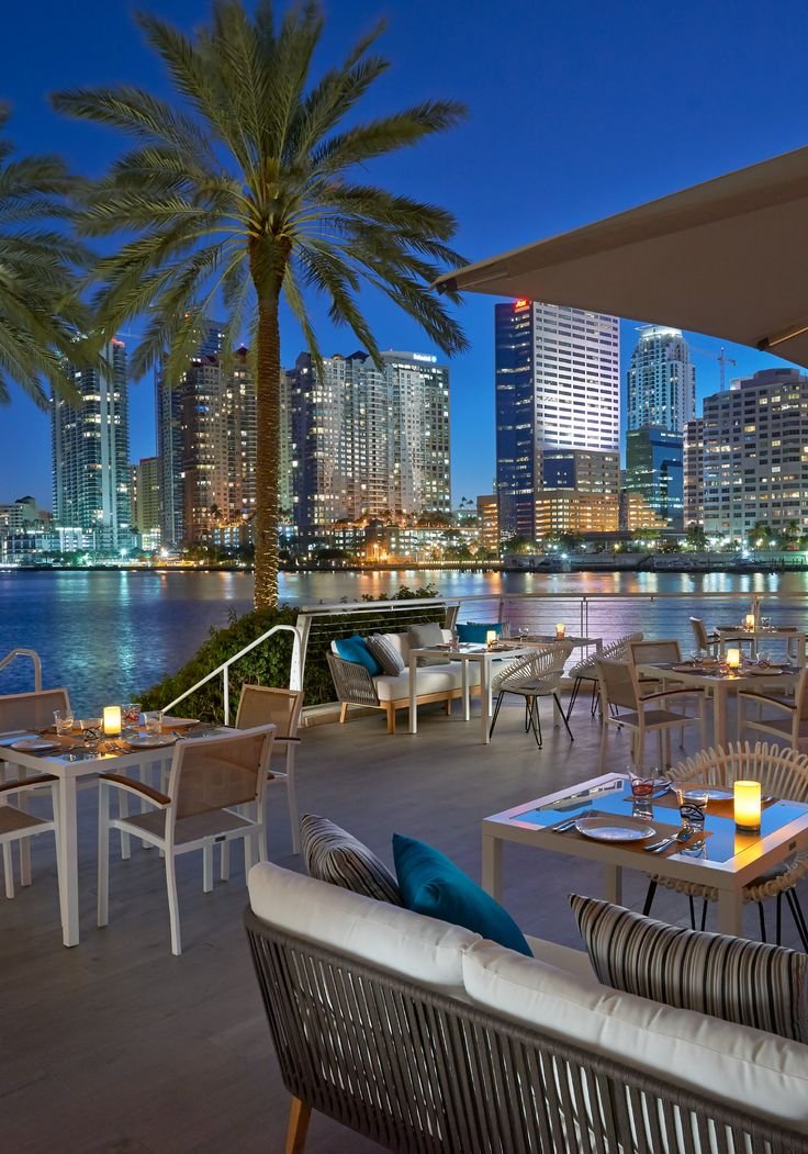 This may contain: an outdoor dining area overlooking the water at night