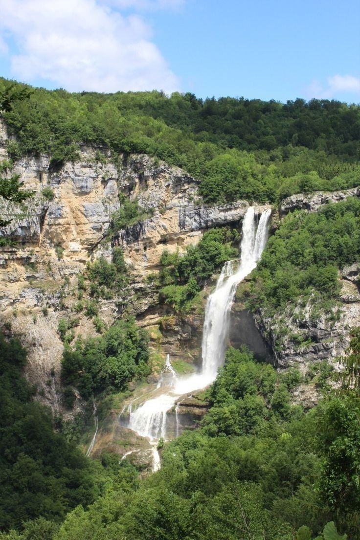 This may contain: a large waterfall in the middle of a lush green forest