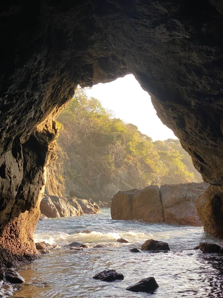 This may contain: the water is flowing under an arch in the rock formation that looks like it's coming out of the cave