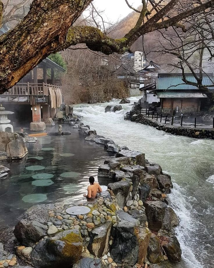 This may contain: a man is sitting on rocks by the water
