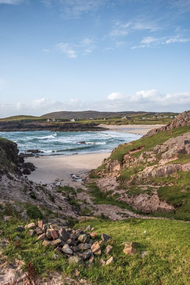 This may contain: the beach is surrounded by rocks and green grass