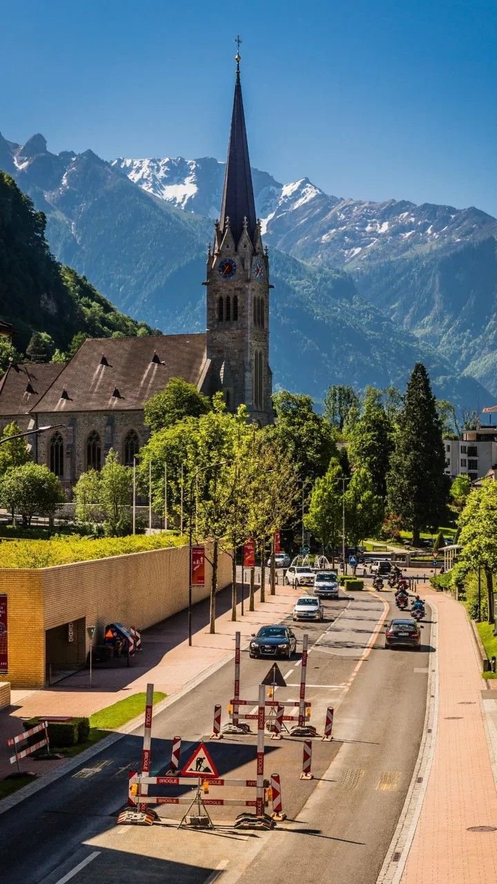 This may contain: a church with a steeple in the background on a mountain road near traffic signs