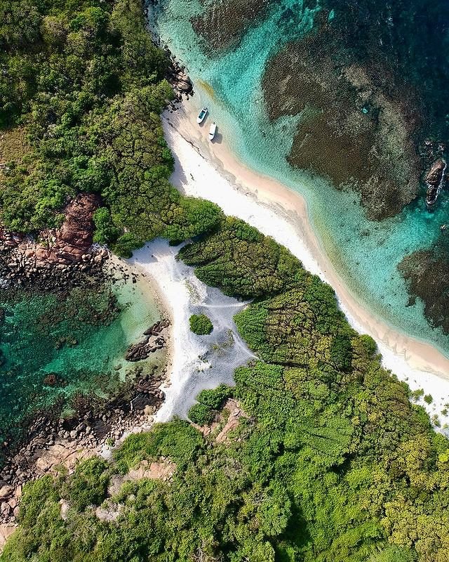 This may contain: an aerial view of the beach and water from above, with boats on it's shore